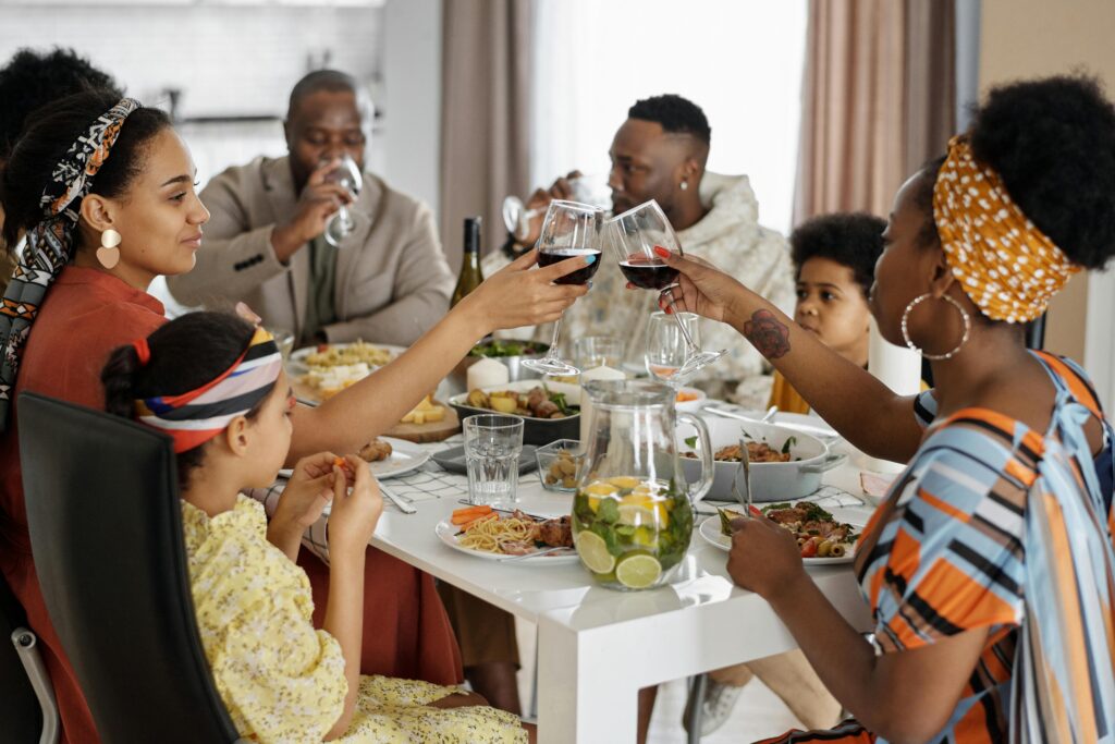 A joyful family gathering sharing a meal indoors, celebrating with wine and delicious food.